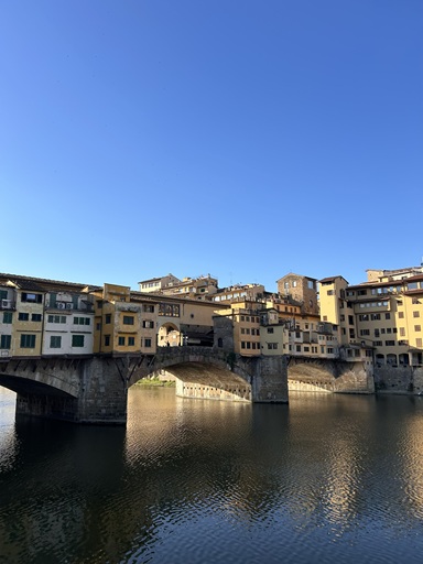 早朝のポンテ・ベッキオ、静かな水面に映る中世の商店街の橋。