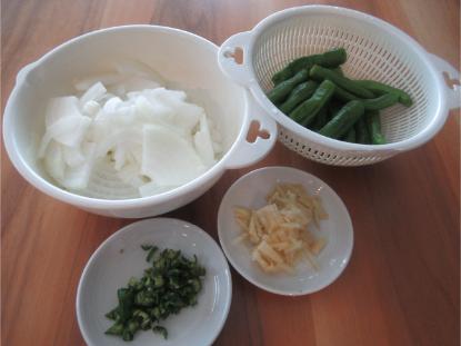 白い大皿に綺麗に並べられたスライスした玉ねぎ、ししとう、千切り生姜の材料写真