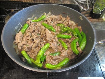 だし汁と醤油ベースの甘辛いつゆに、ししとうとみじん切り青唐辛子を加えてフライパンで煮込んでいる様子