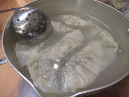 大き目の行平鍋に沸騰したお湯でふっくらと茹でられている、手作りの大ぶりな水餃子